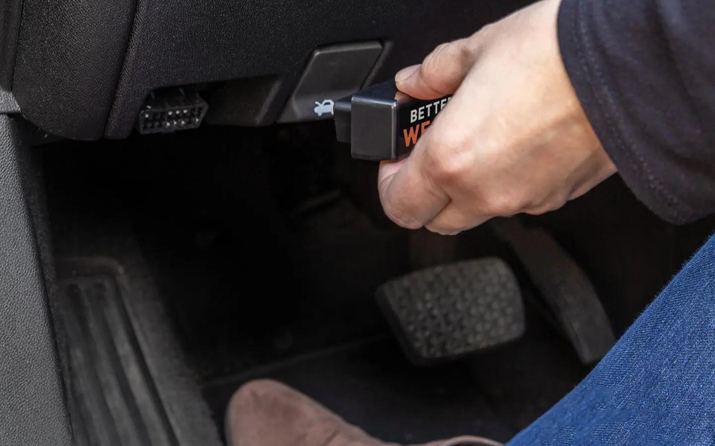 A handheld OBD-II scanner plugged into a car’s diagnostic port showing trouble codes on its screen