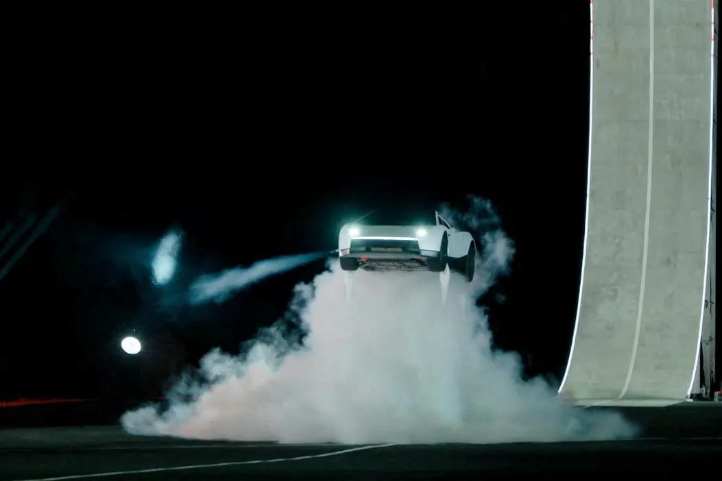 A next-generation Tesla Roadster launching off a curved ramp at a SpaceX test site in McGregor, Texas, captured midair as it begins a flip