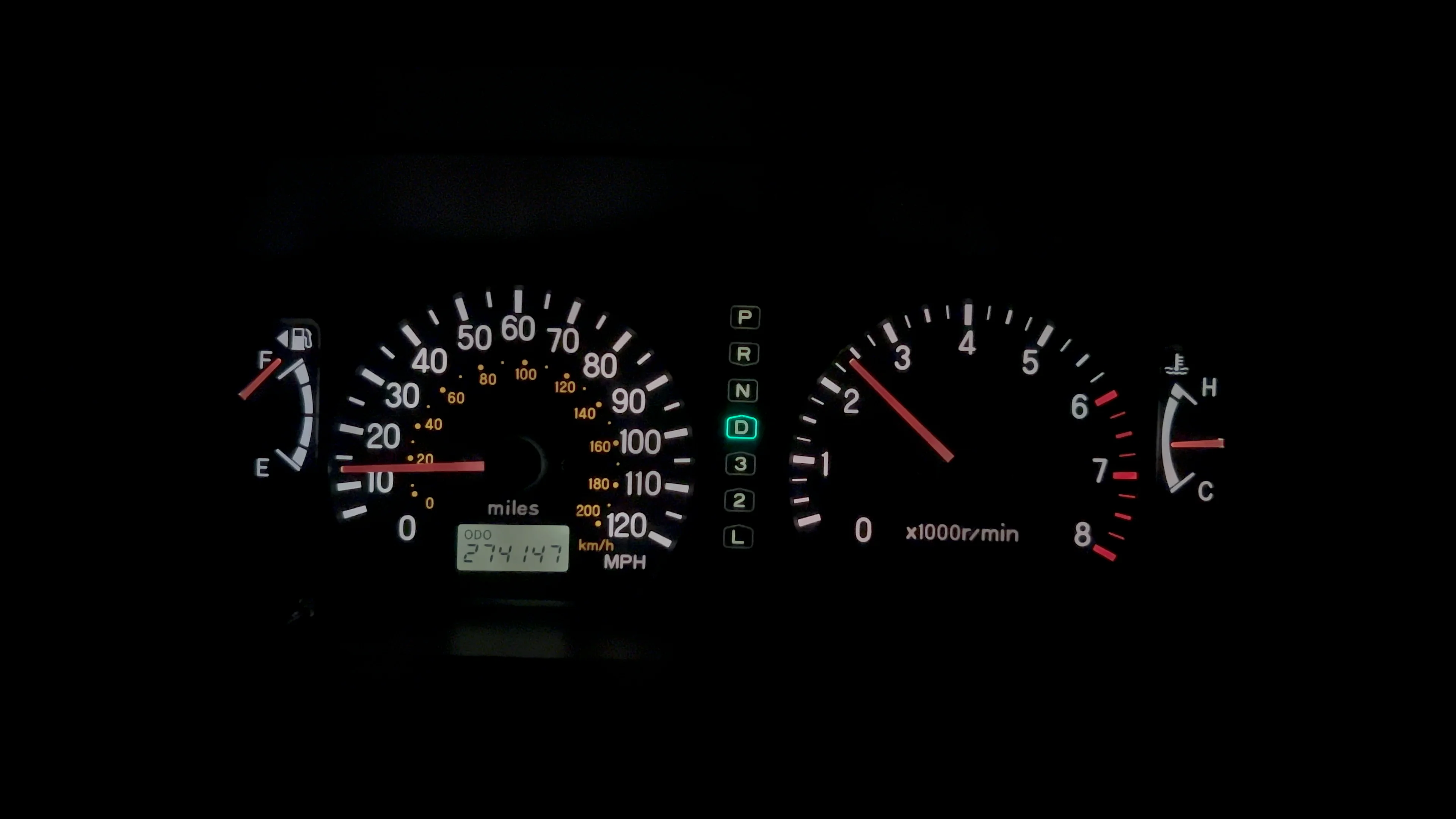View from the driver seat showing a tachometer needle jumping upward while driving, suggesting rpm flare during a shift